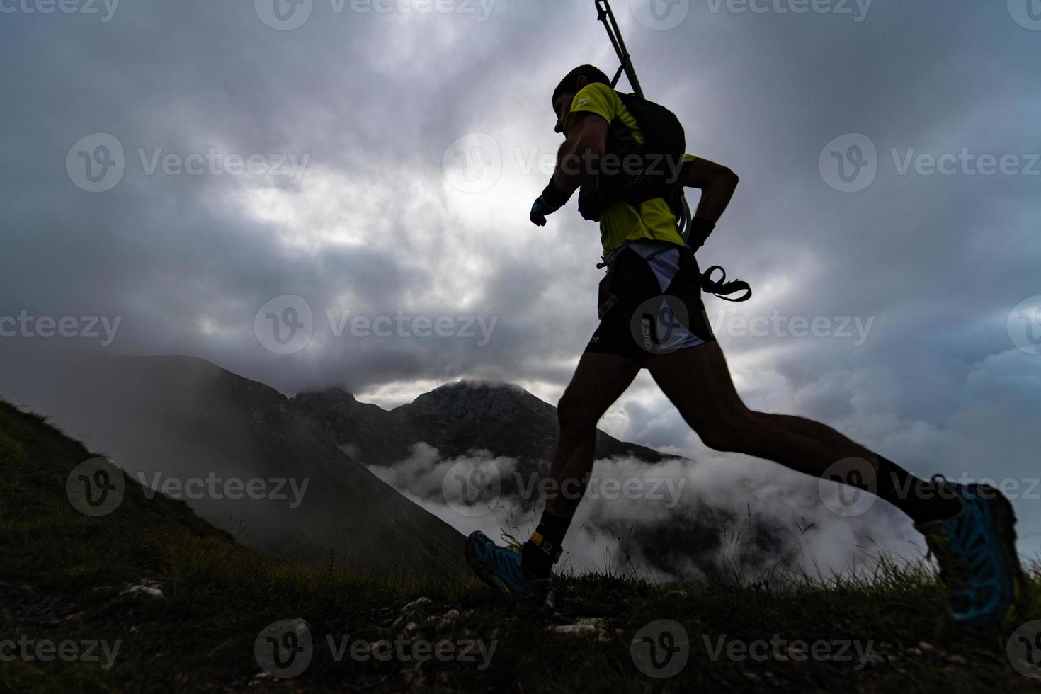 Extremer Bergrennen-Wettkampf Skymarathon. Sportler läuft mit Stöcken im Rucksack foto