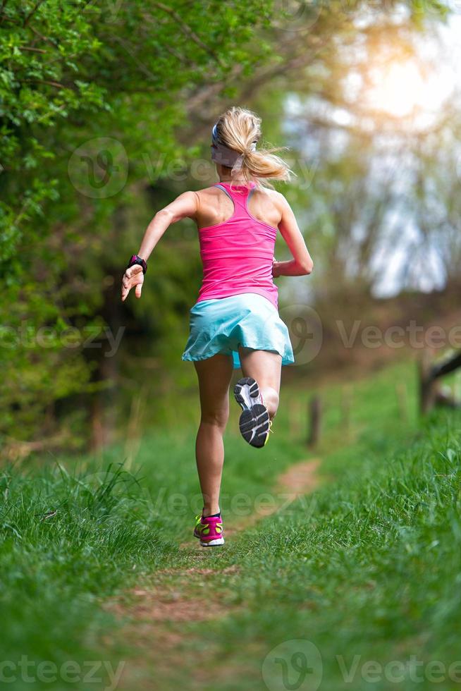 Blonde Sportlerin läuft auf einem Trail in den Wald foto