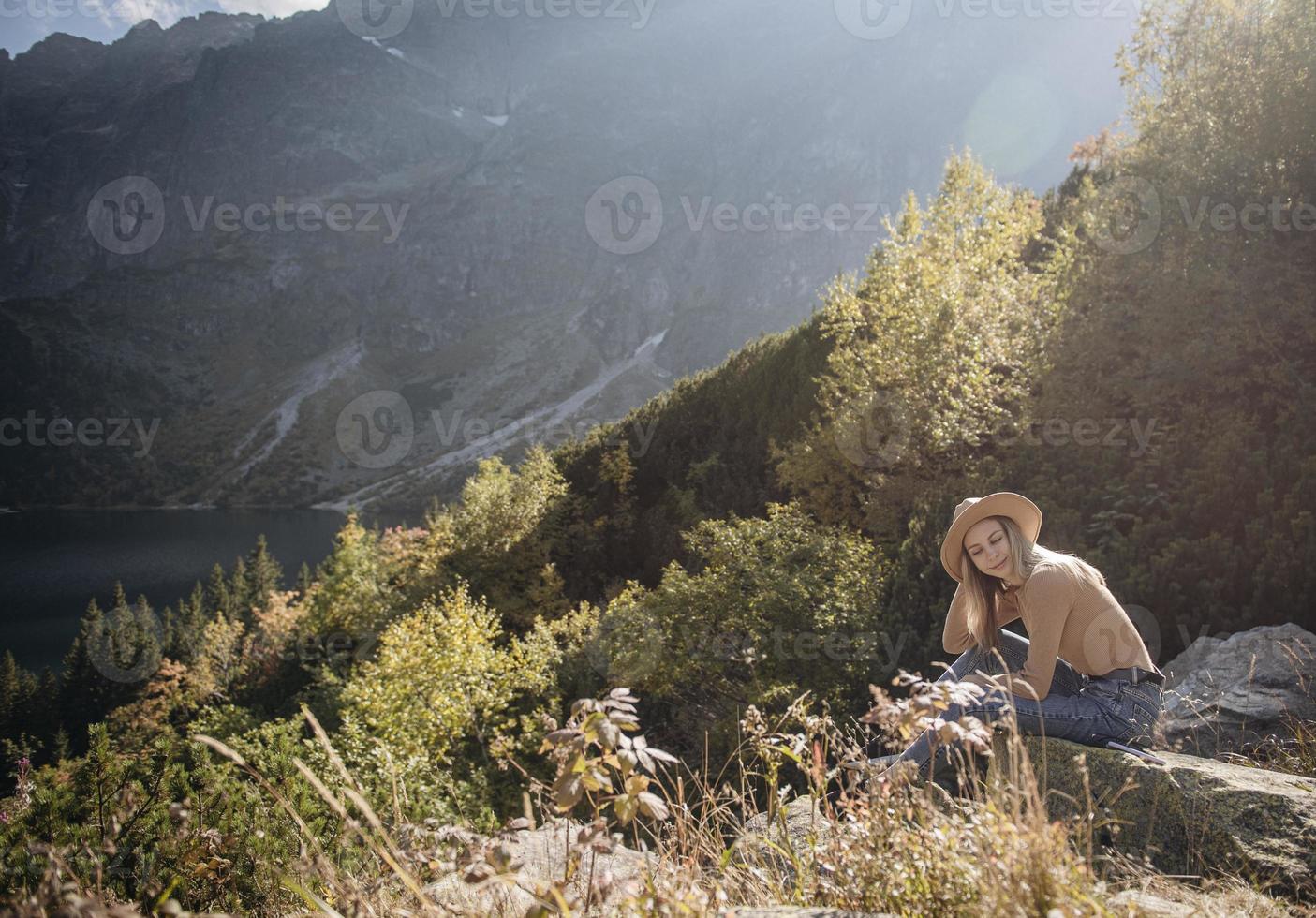 junge frau auf einer wanderung, die auf einem felsen sitzt foto