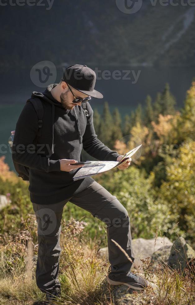 junger mannreisender mit karte und rucksack foto