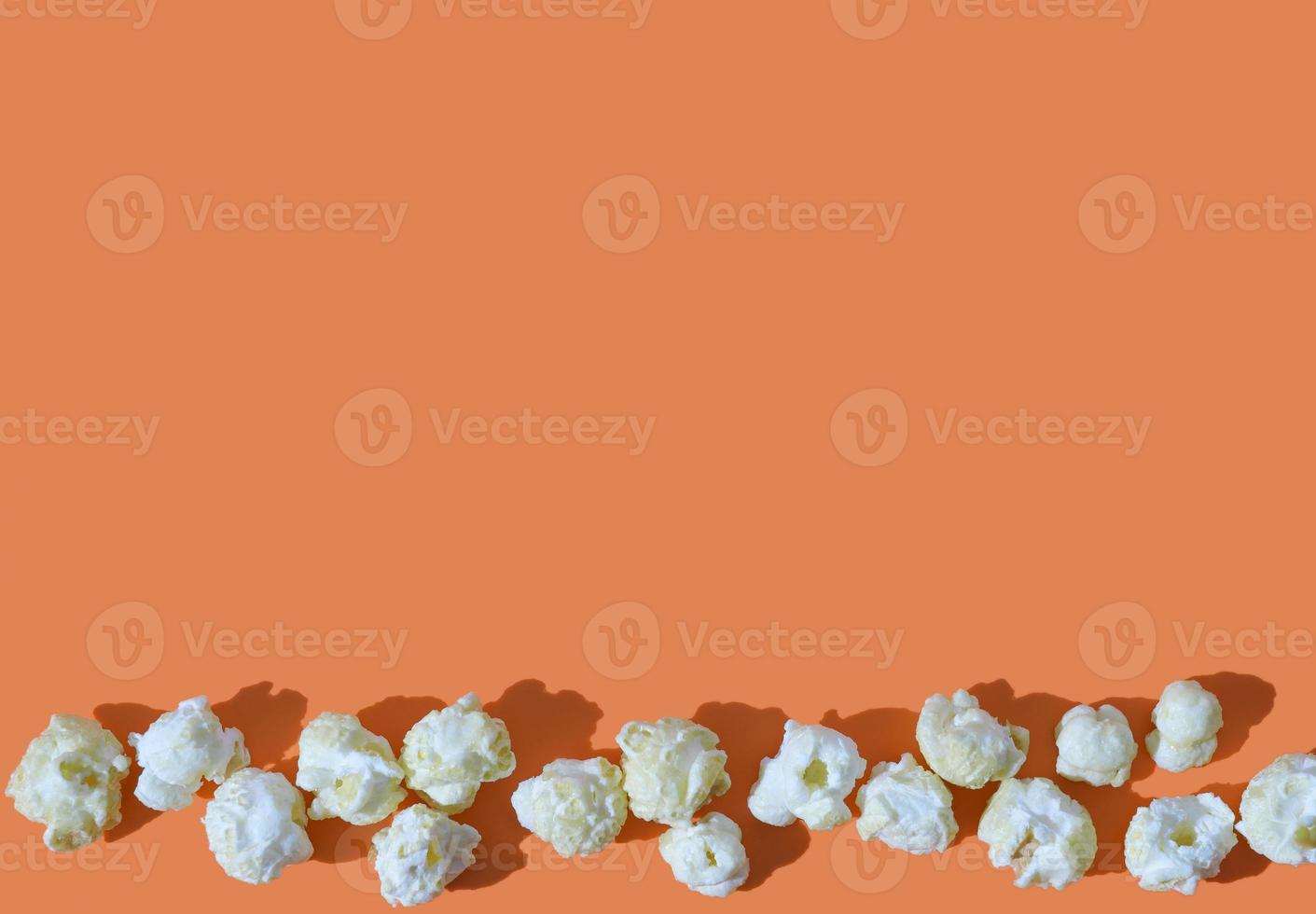 salziges Popcorn auf orangefarbenem Hintergrund. Platz kopieren. foto