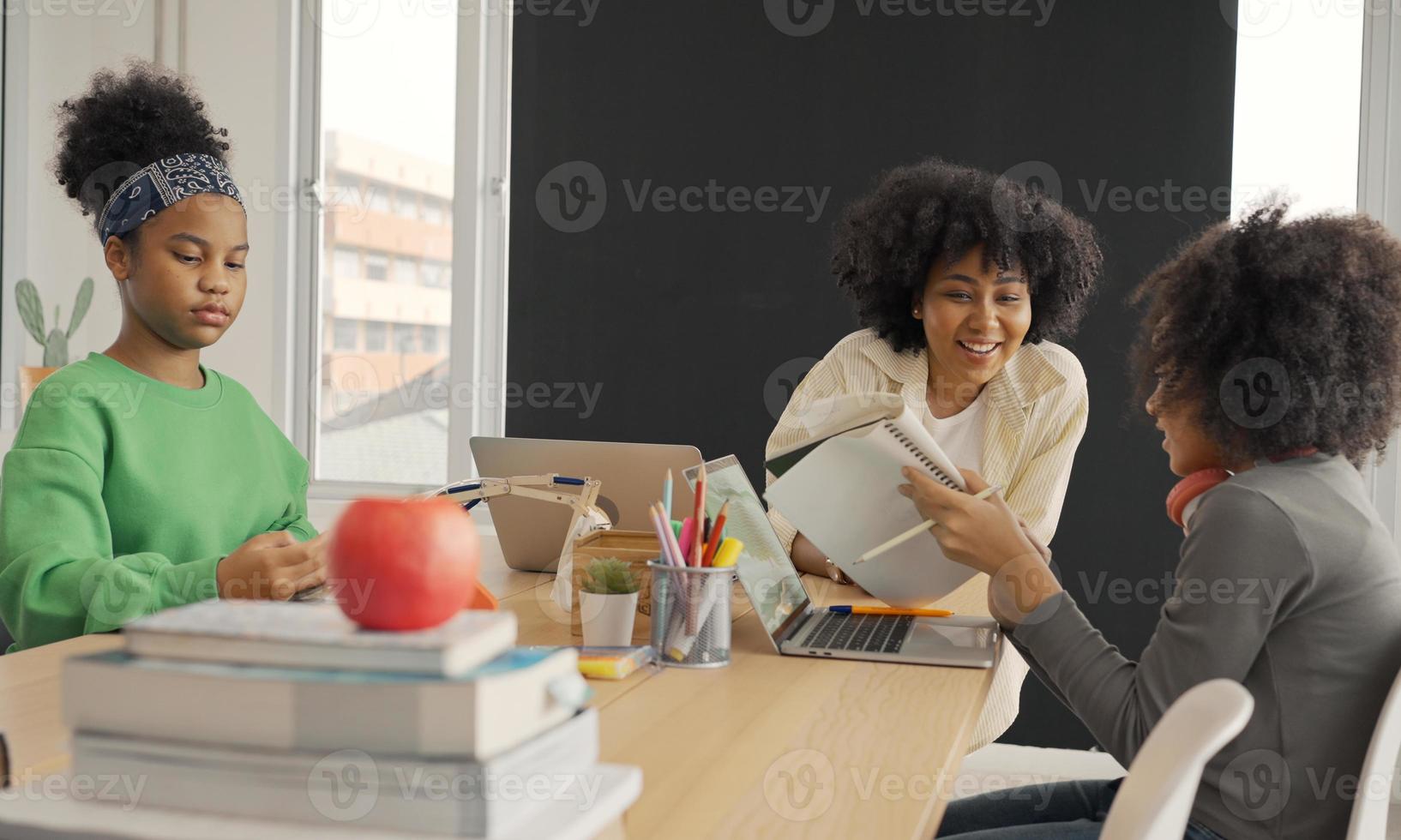 Klassenzimmer mit verschiedenen Lernenden von fröhlichen afroamerikanischen Schülern und Lehrern, die gemeinsam Aktivitäten unternehmen. Der Lehrer unterrichtet, leitet und spricht mit den Kindern in verschiedenen Bereichen. foto