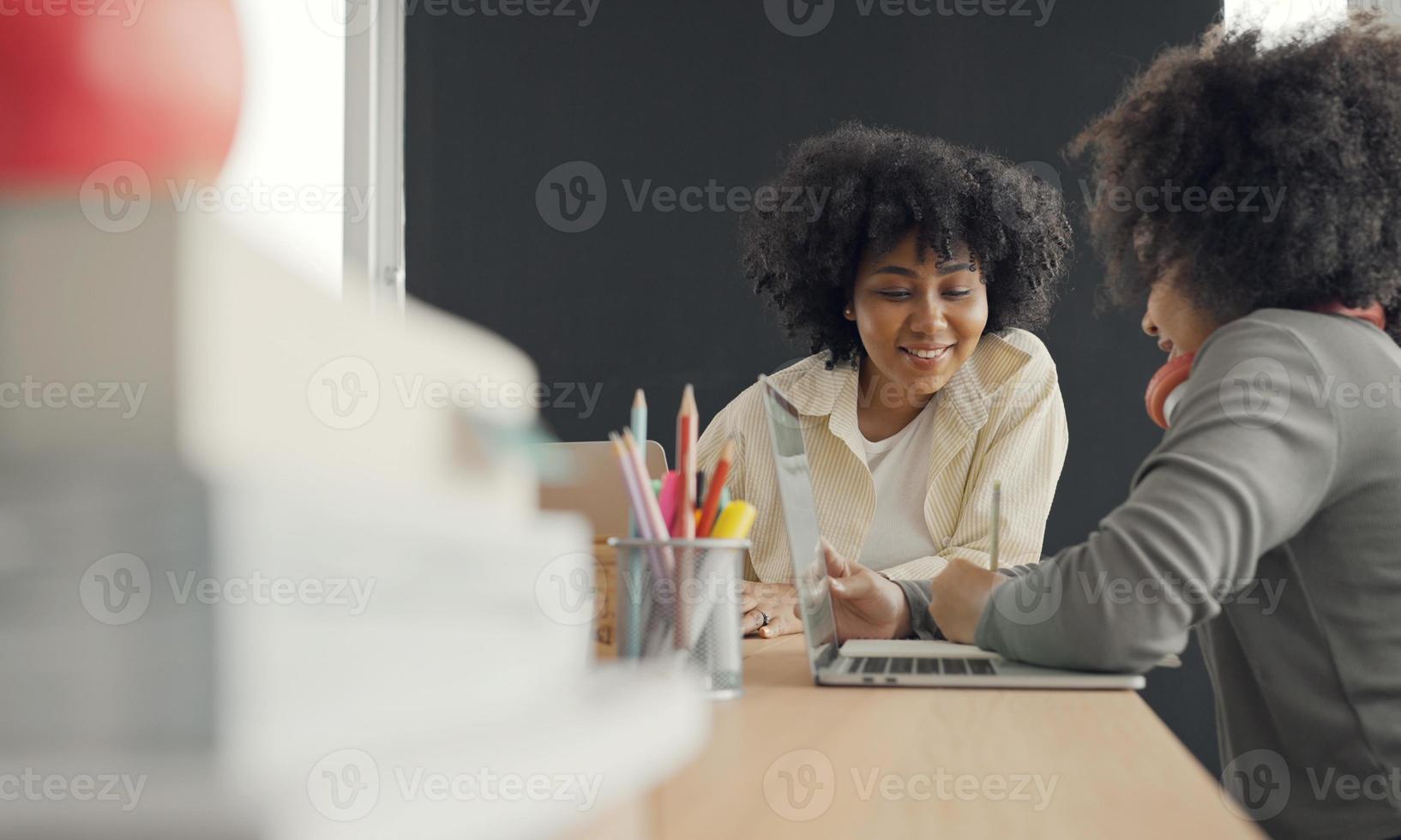 Klassenzimmer mit verschiedenen Lernenden von fröhlichen afroamerikanischen Schülern und Lehrern, die gemeinsam Aktivitäten unternehmen. Der Lehrer unterrichtet, leitet und spricht mit den Kindern in verschiedenen Bereichen. foto