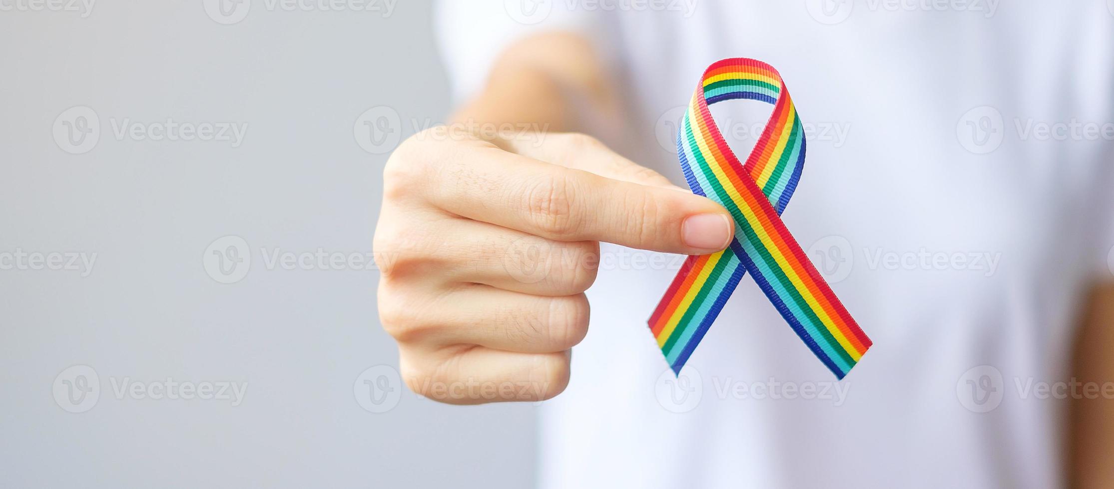 Hand, die ein lgbtq-Regenbogenband hält, um das Konzept der Lesben-, Schwulen-, Bisexuellen-, Transgender- und Queer-Gemeinschaft und des Stolzmonats zu unterstützen foto