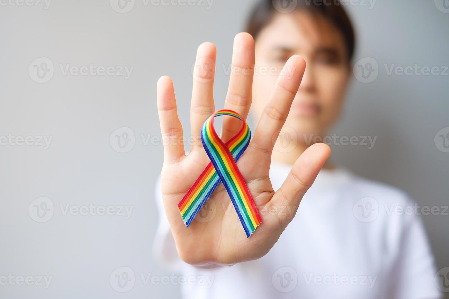 Hand, die ein lgbtq-Regenbogenband hält, um das Konzept der Lesben-, Schwulen-, Bisexuellen-, Transgender- und Queer-Gemeinschaft und des Stolzmonats zu unterstützen foto