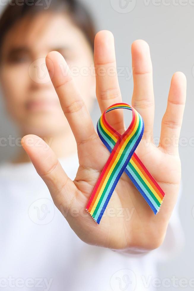 Hand, die ein lgbtq-Regenbogenband hält, um das Konzept der Lesben-, Schwulen-, Bisexuellen-, Transgender- und Queer-Gemeinschaft und des Stolzmonats zu unterstützen foto