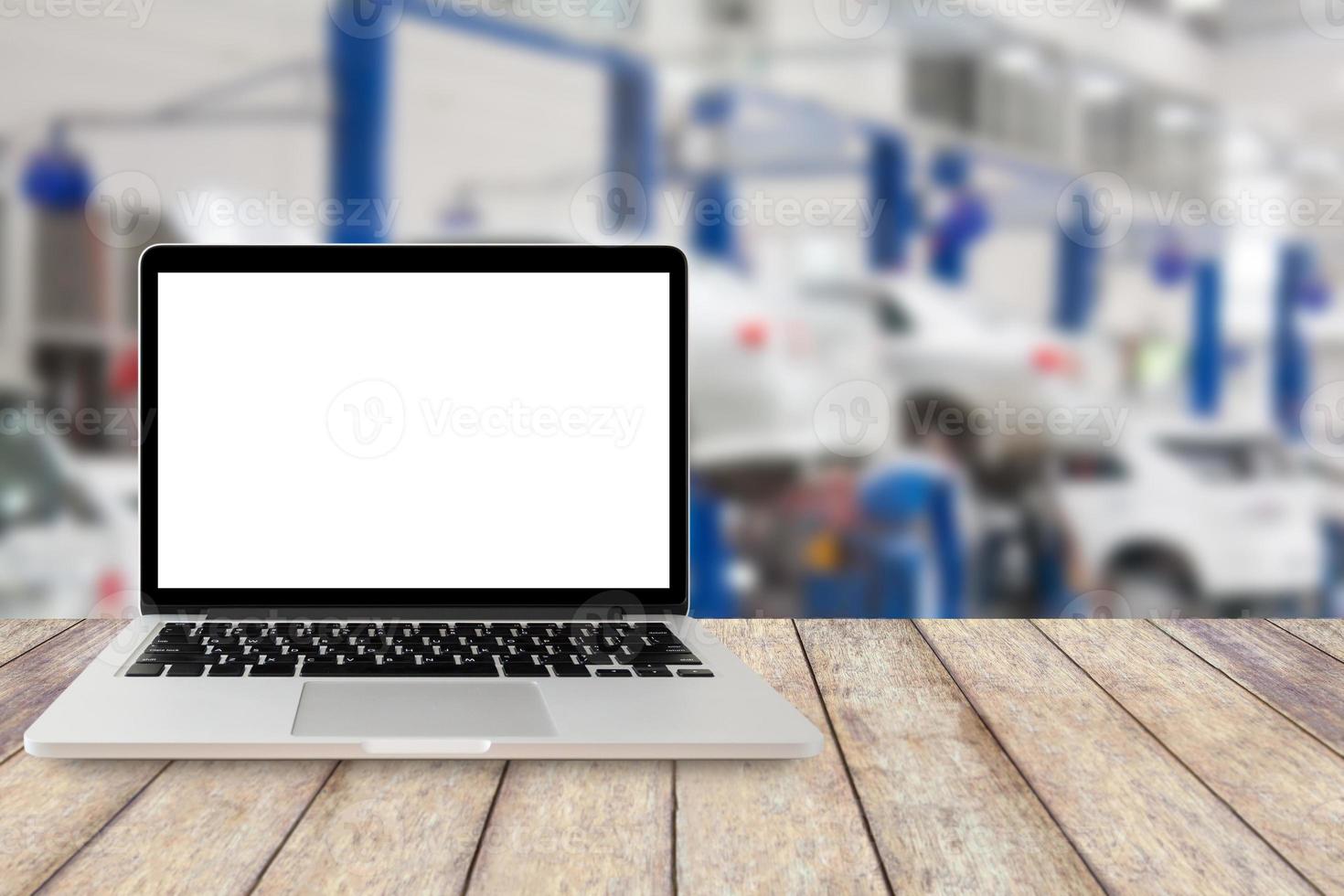 Laptop auf Holztisch mit verschwommenem Auto-Service-Center-Hintergrund foto