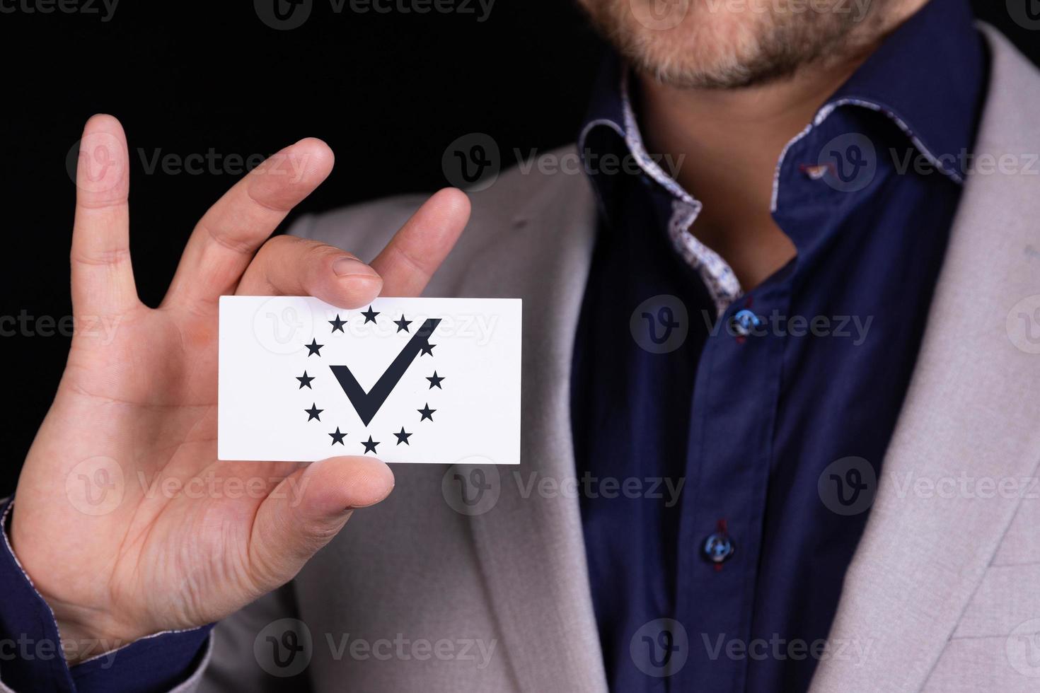 Ein Geschäftsmann zeigt vor sich eine Visitenkarte mit einem Häkchen, einem genehmigten Symbol in einem Kreis aus Sternchen. Konzept kommen Sie zu uns. foto