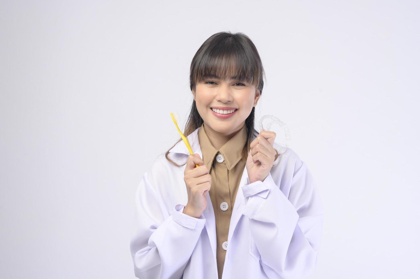 junger weiblicher Zahnarzt, der über weißem Hintergrundstudio lächelt foto