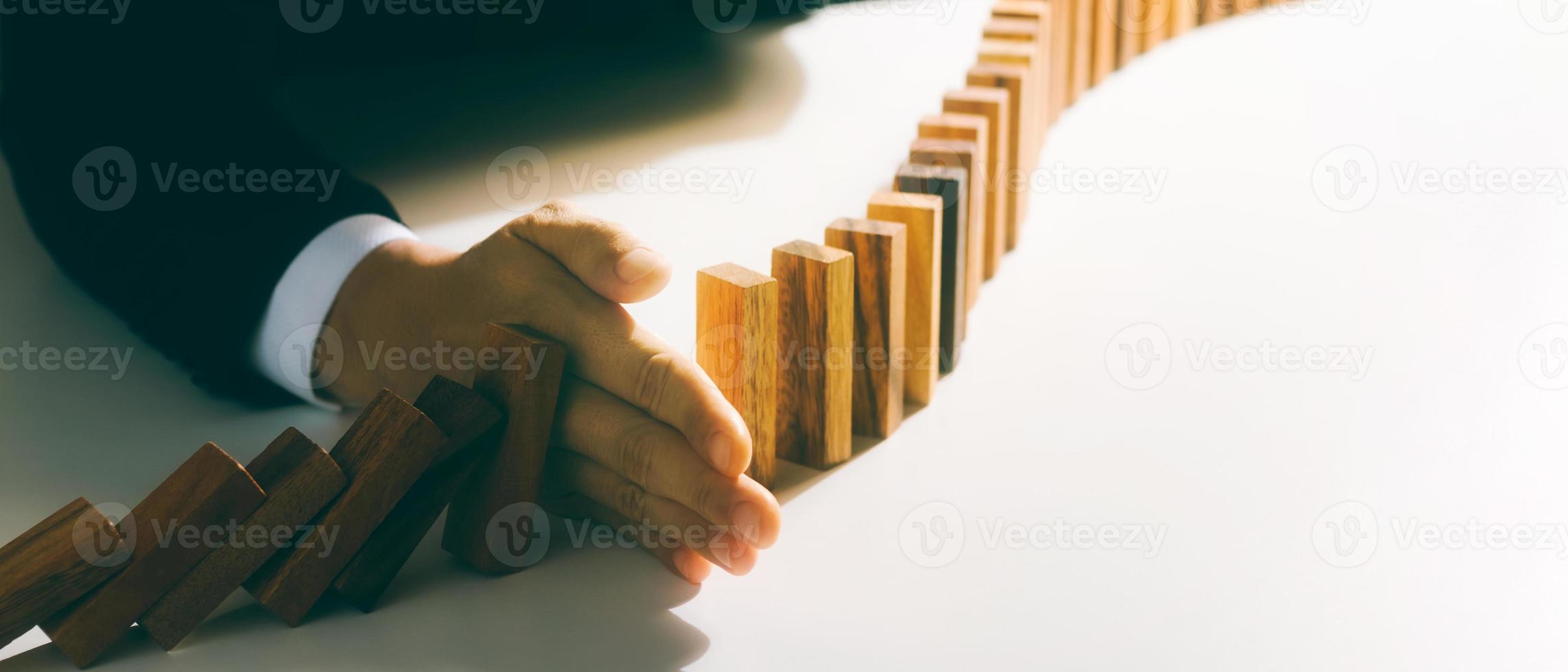 risikomanagement, geschäftsmannhand stoppt das kontinuierliche fallen von holzdominosteinen, stoppt die auswirkungen der geschäftskrise. Absicherung von Geschäftsproblemen für den Erfolg. foto