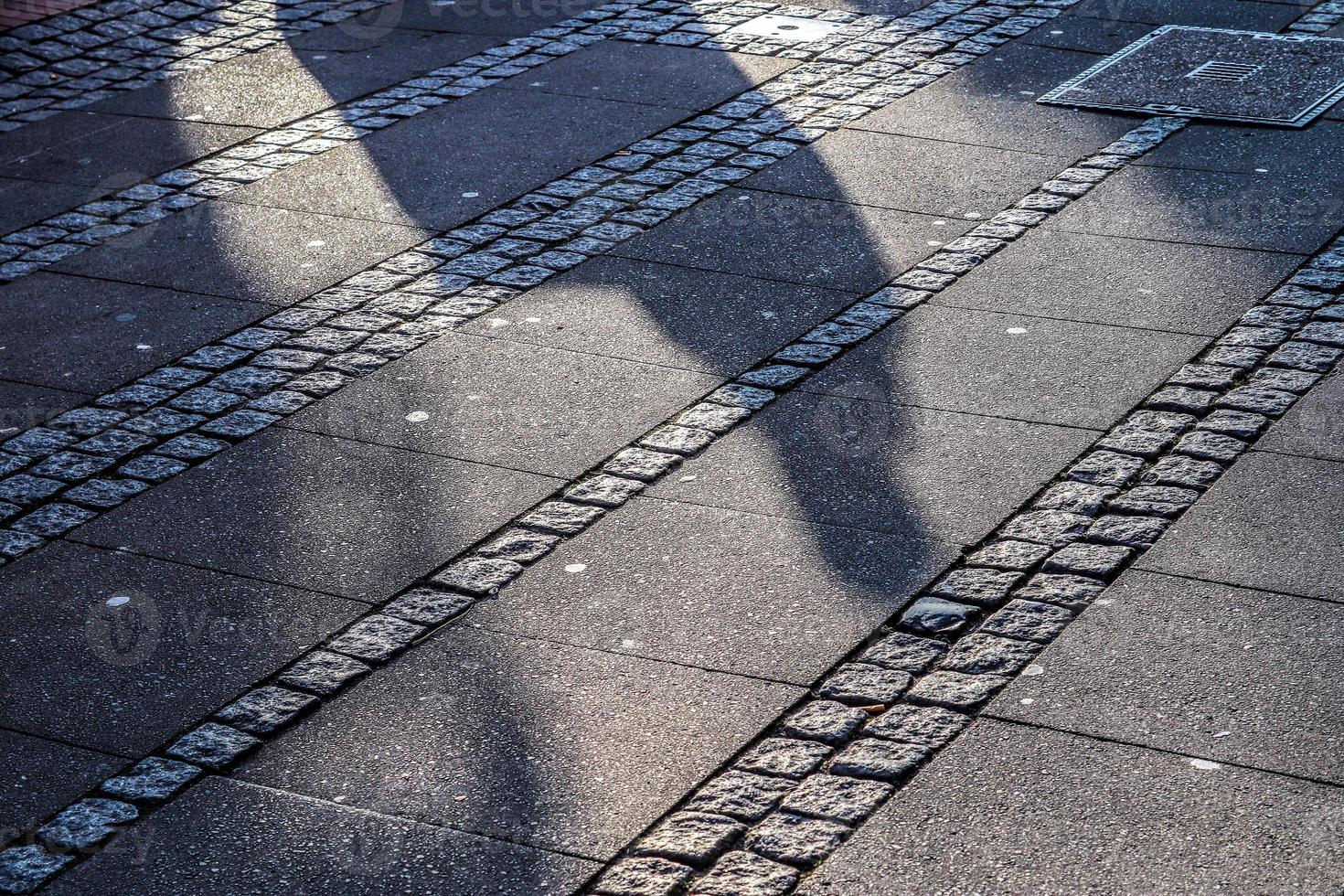 Schatten von Menschen in einem europäischen Einkaufsviertel auf einem Kopfsteinpflaster foto