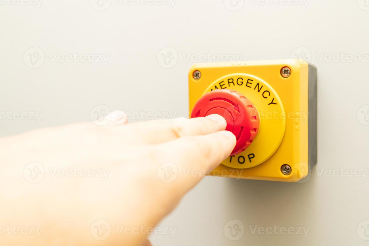 stoppknopf und die hand des arbeiters, der ihn drückt. Notaus-Knopf. großer roter Notknopf oder Stoppknopf zum manuellen Drücken. foto