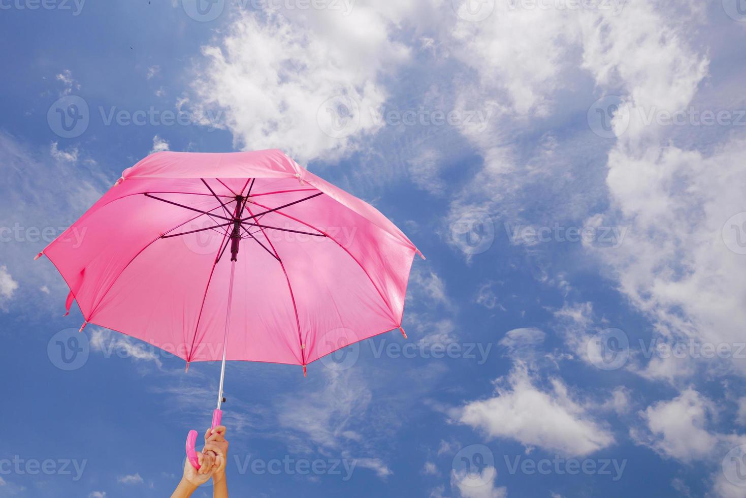 Zwei Hände halten einen Regenschirm am blauen Himmel foto