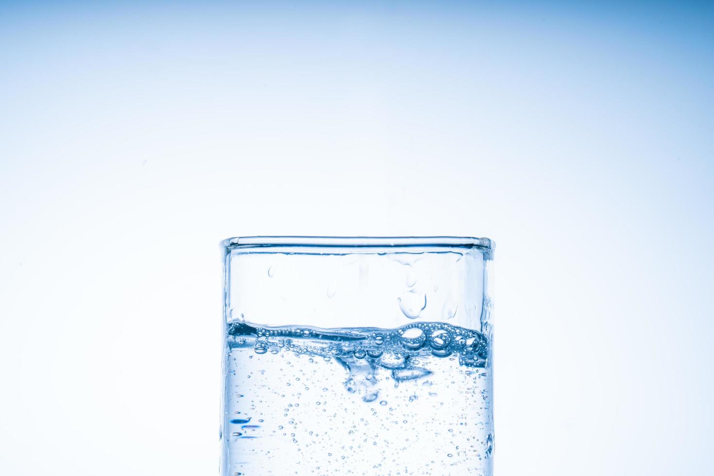 Eiswürfel fiel in das Wasserglas. Wasser spritzte aus dem klaren Glas. frisches Konzept foto