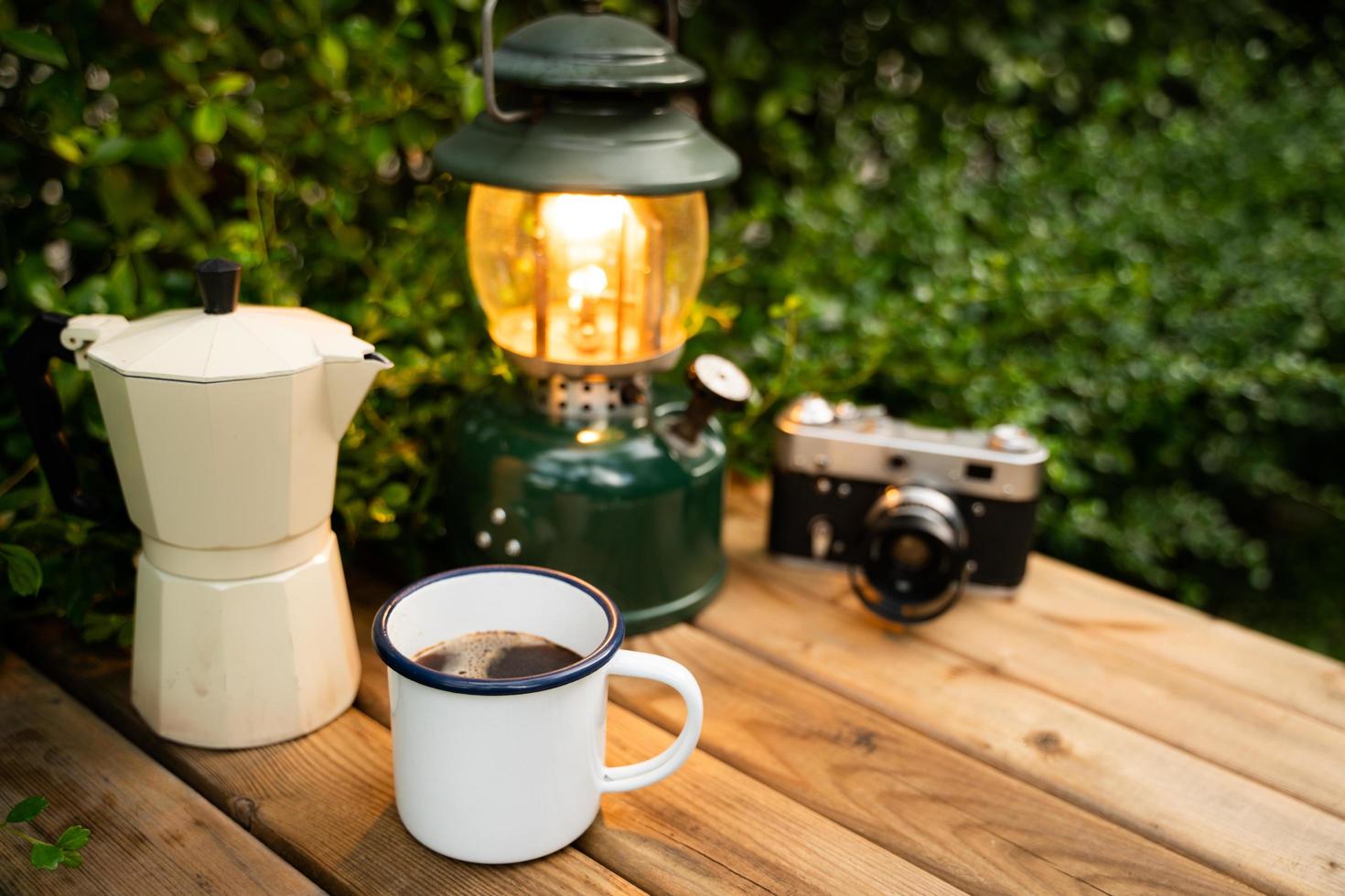 Selektiver Fokus weiße Emaille-Kaffeetasse und Kaffeeset im Garten mit alten Laternen in Campingatmosphäre. Weicher Fokus. foto