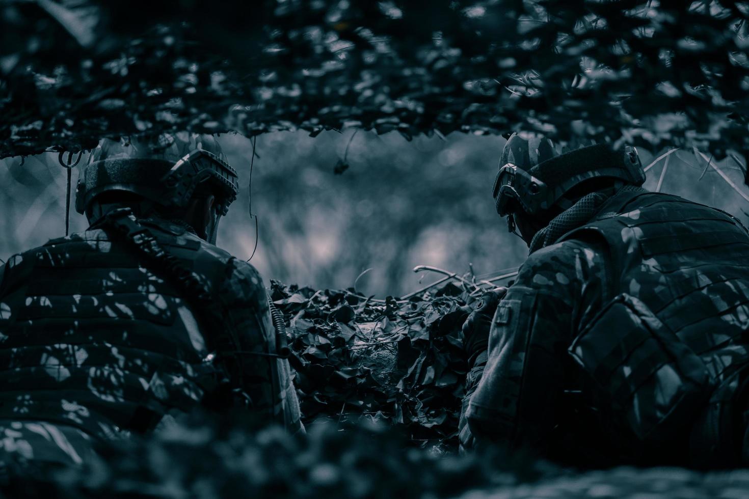 Rückansicht von Soldaten auf dem Schlachtfeld, Militärstützpunkt, Mission im Gange, nachts im Wald foto