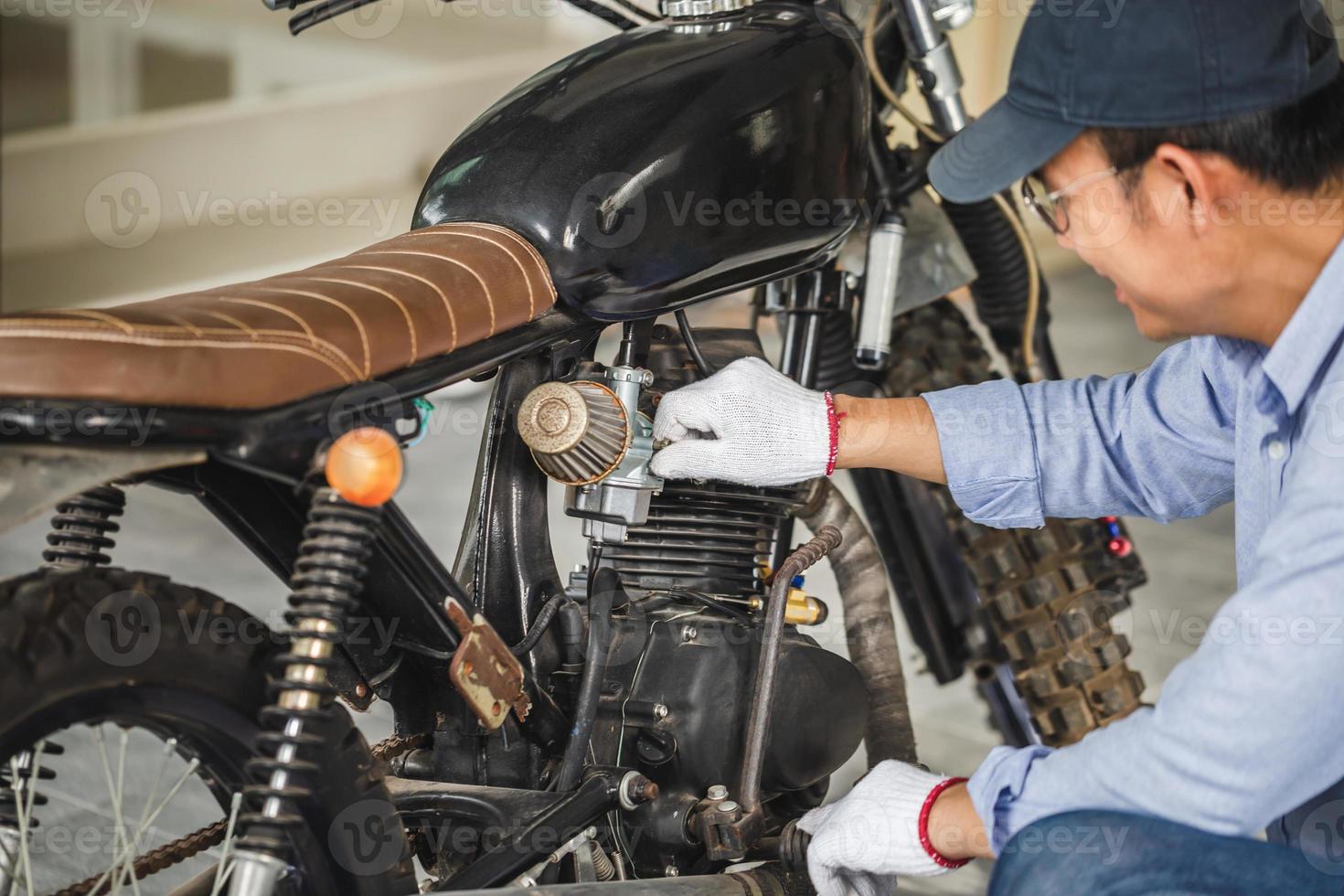 junger mann, der motorrad in der werkstatt repariert, mann, der motorrad in der werkstatt repariert, mechanisches hobby und reparaturkonzepte foto