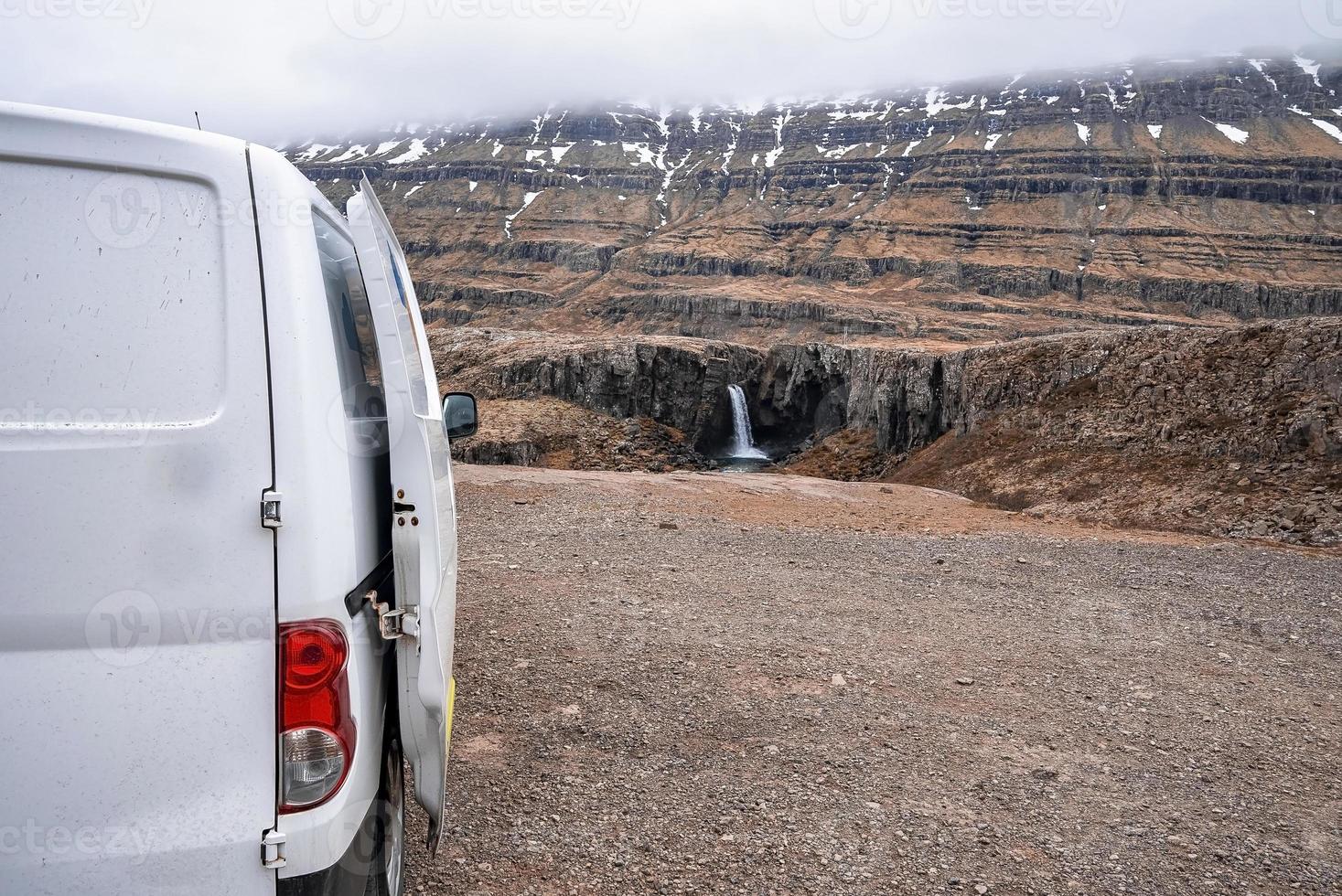 Van geparkt auf einer Klippe mit Blick auf den Folaldafoss-Wasserfall gegen den Berg im Tal foto