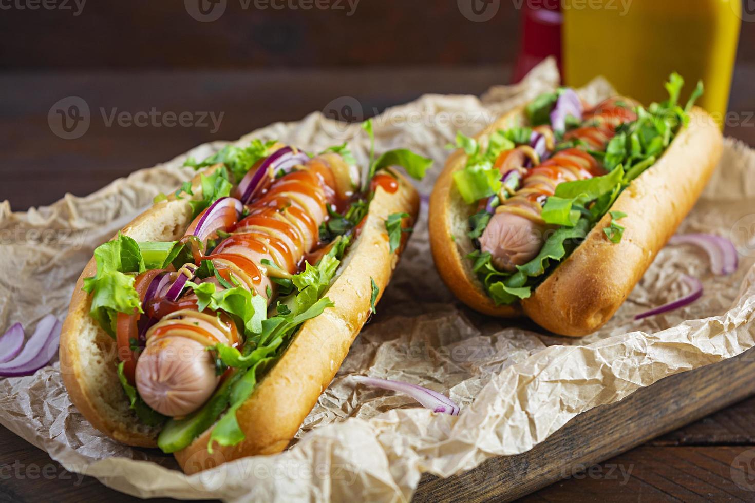 Hausgemachter Hot Dog mit Wurst, Salat, Karotten, Gurken und Tomaten auf Holzhintergrund foto