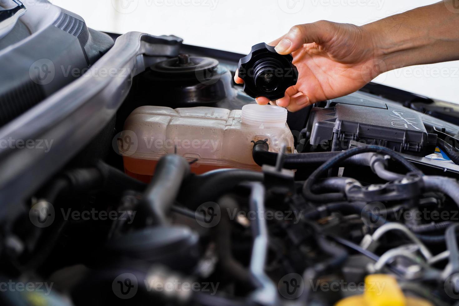 Mechaniker inspiziert den Ausgleichsbehälter mit rosafarbenem Frostschutzmittel. Fahrzeugkühlmittelstand im Kühlersystem des Autos. Autoteile foto