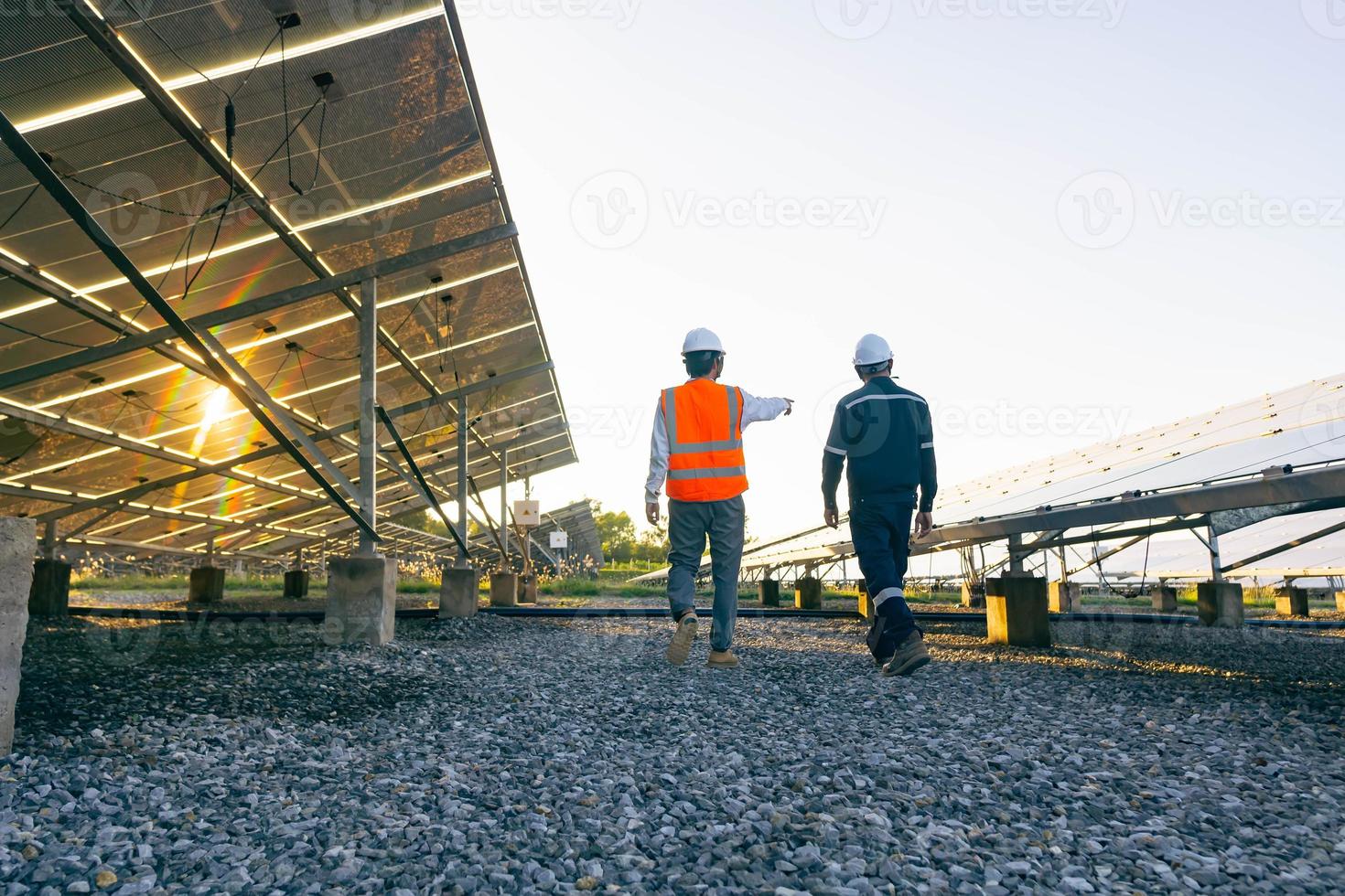 Tiefwinkelansicht des Technikers geht mit Investor durch das Feld der Sonnenkollektoren, alternative Energie zur Einsparung der Energie der Welt, Photovoltaik-Modul-Idee für saubere Energieerzeugung foto