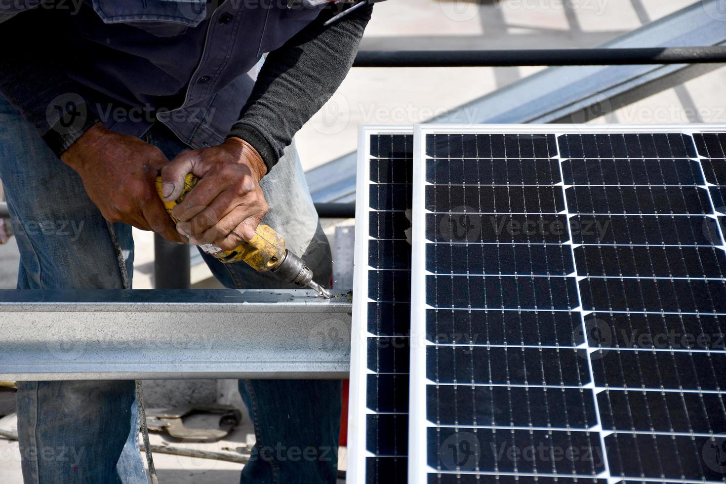 Der Techniker bohrt Löcher, um die Solarzelle mit einer elektrischen Bohrmaschine zu montieren foto