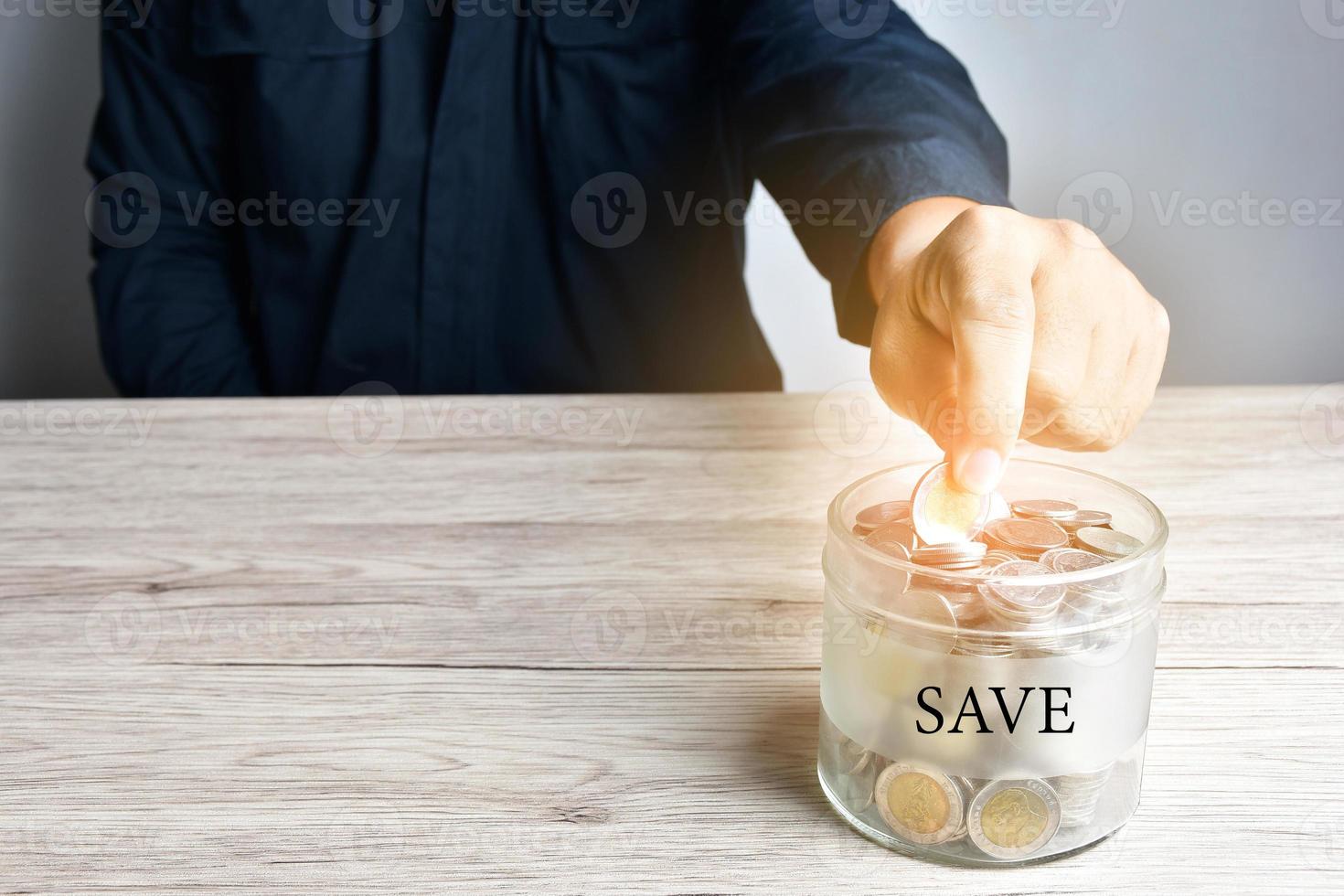 Ein Geschäftsmann steckte eine Münze in ein Glas oder kämpfte als Ersparnis in der Bank, wenn sie voll war. foto