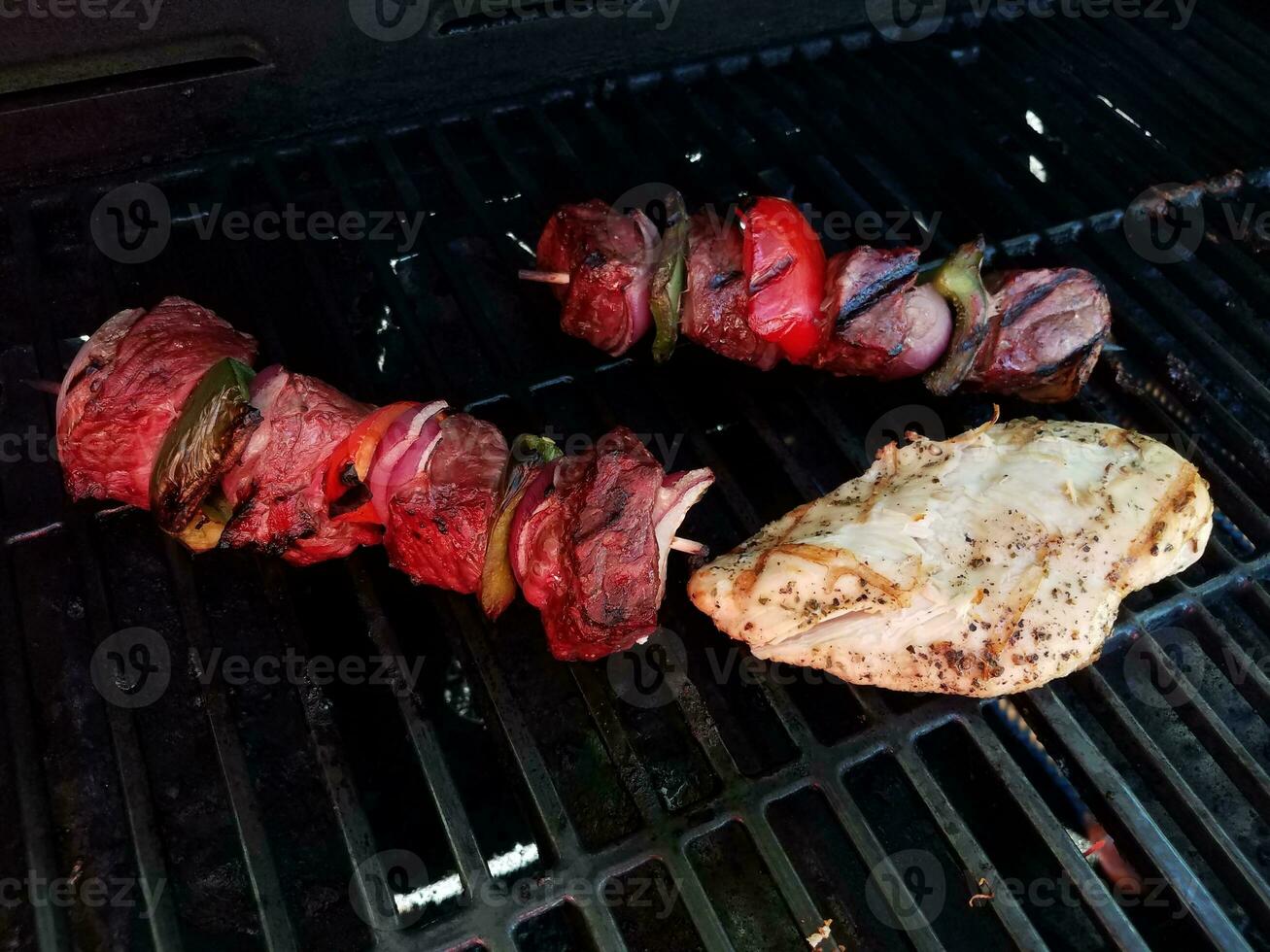 Rindfleisch-Kebab mit Zwiebeln und Paprika am Spieß auf einem Grill mit Hähnchen foto