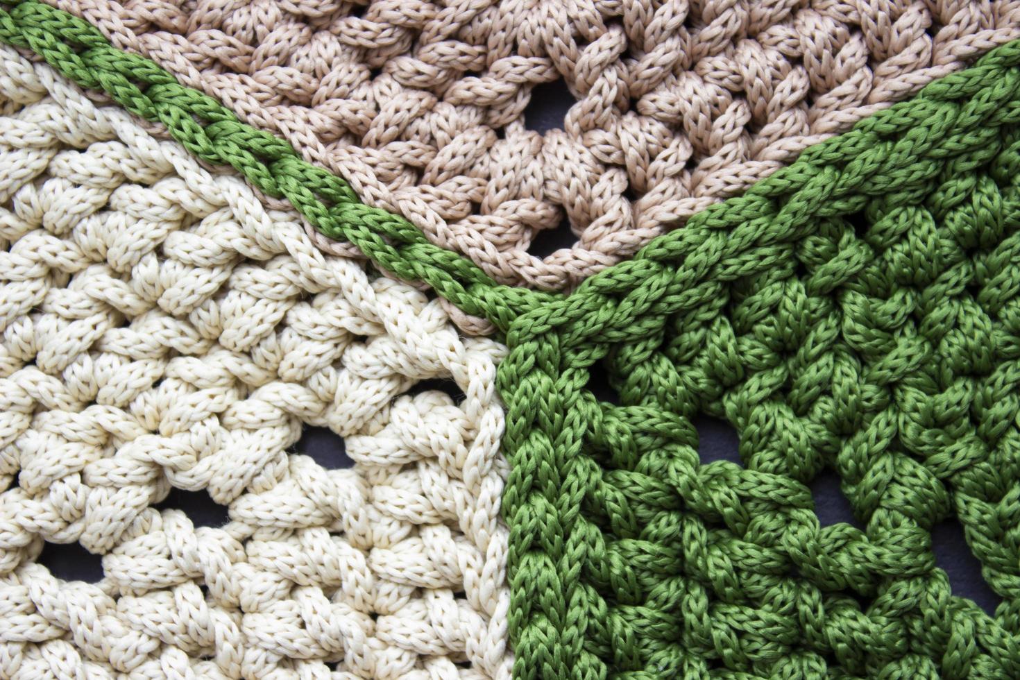 Stricken aus einer Schnur. gehäkelter Teppich aus Sechsecken. beige und grün. Stricktextur. foto