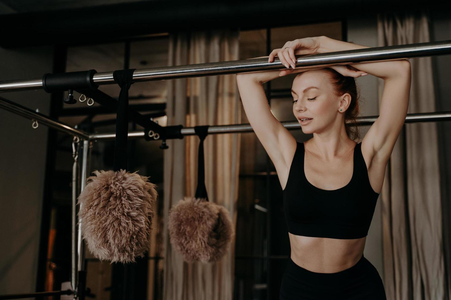 schöne rothaarige fitnessfrau, die sich auf pilates cadillac reformer entspannt foto