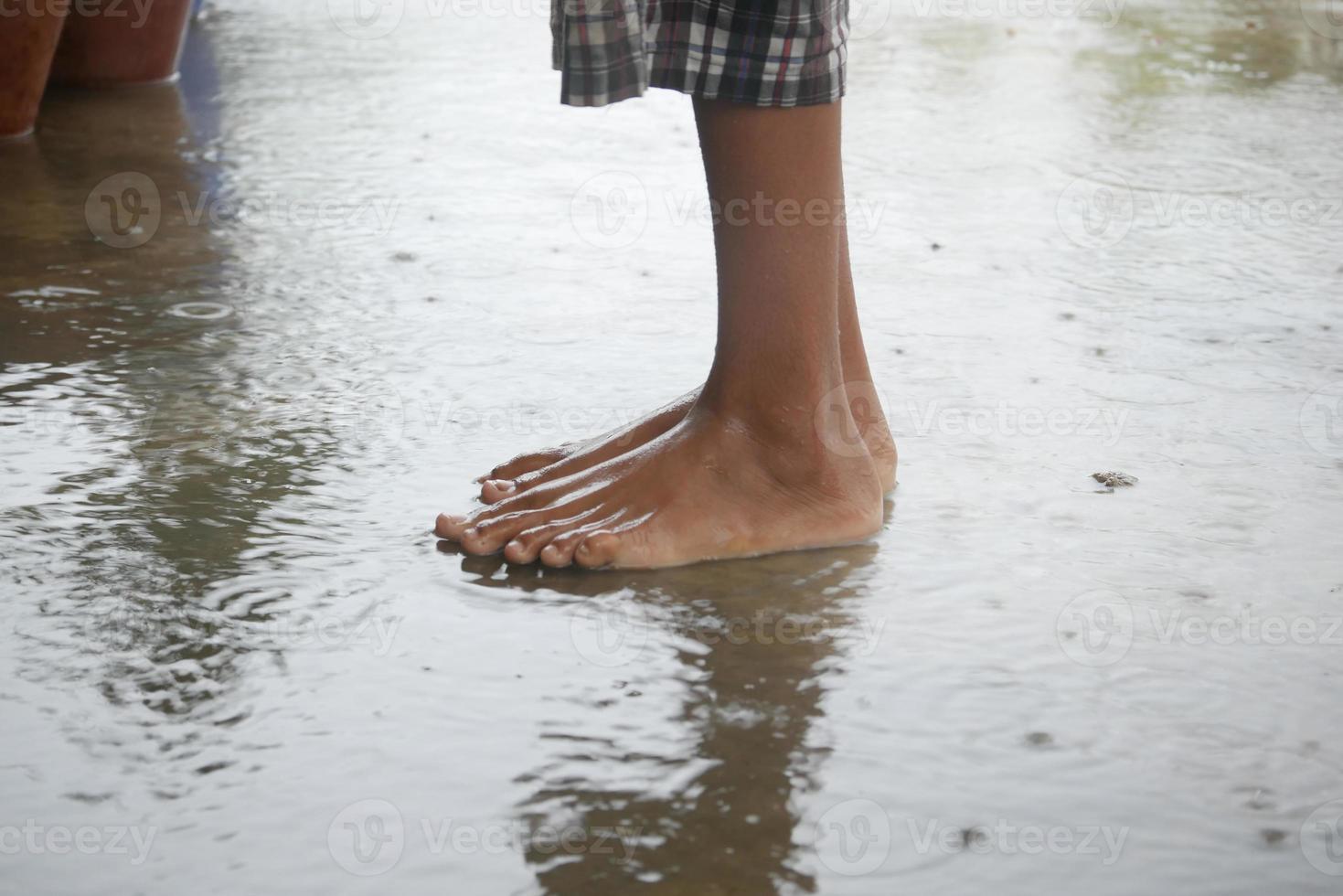 Kind springt nach Regen auf Wasserwasser foto