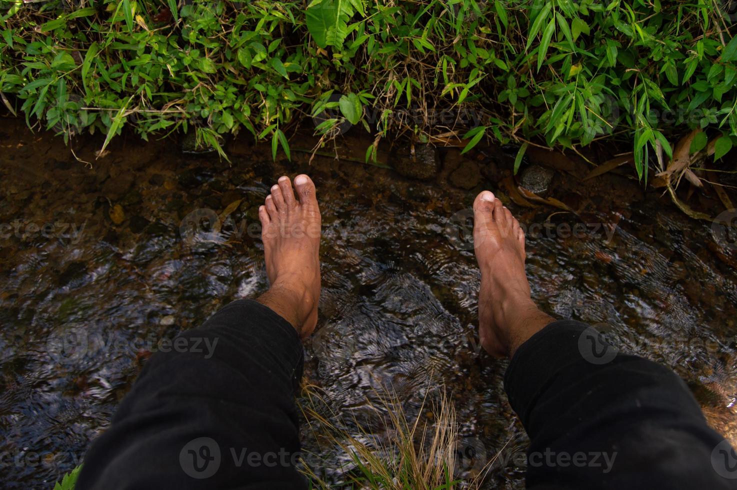 die Füße einer Person, die auf klarem Wasser verweilt foto