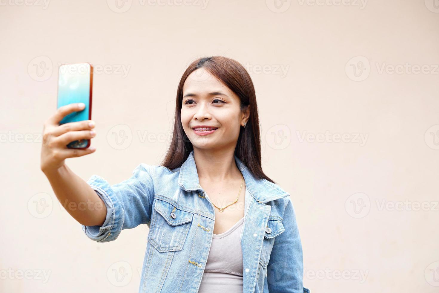 asiatische frau macht glücklich ein selfie mit ihrem telefon. foto