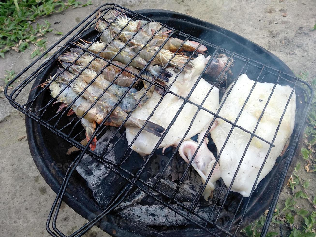 gegrillter Tintenfisch und Garnelen auf dem Grill. udang dan cumi-cumi panggang oder bakar. traditionelles indonesisches essen foto