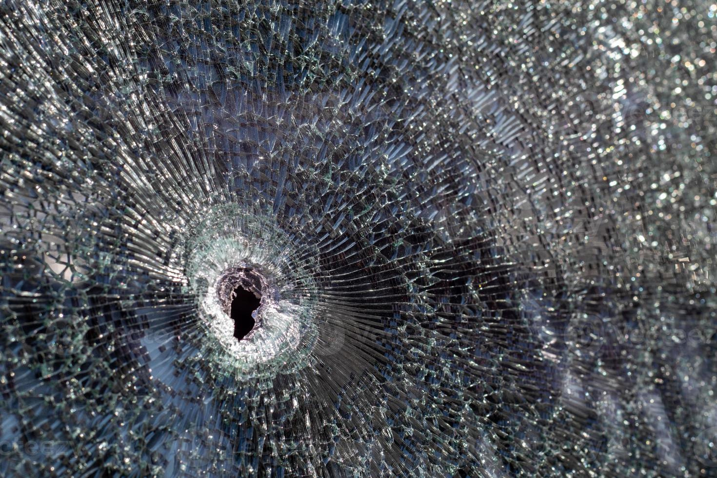 Löcher in der Windschutzscheibe des Autos, es wurde aus einer Schusswaffe geschossen. Einschusslöcher. Windschutzscheibe zerschlagen, kaputtes und beschädigtes Auto. Die Kugel hinterließ ein zerbrochenes Loch im Glas. foto