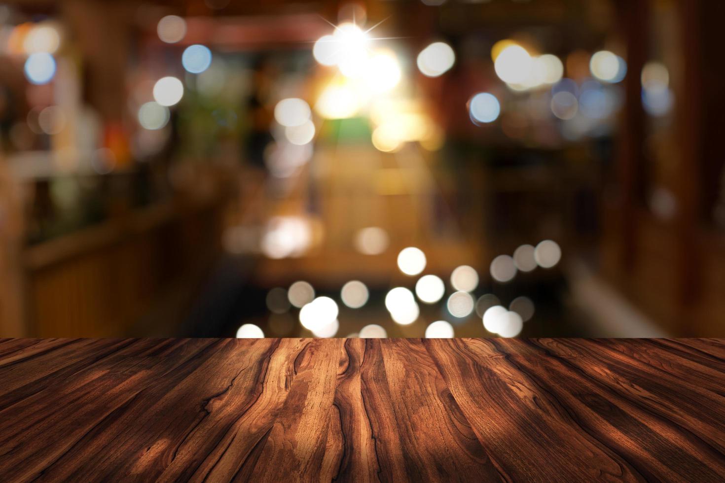 Top-Schreibtisch mit unscharfem Restauranthintergrund, Holztisch und verschwommenem Bokeh des nächtlichen Straßenhintergrunds foto