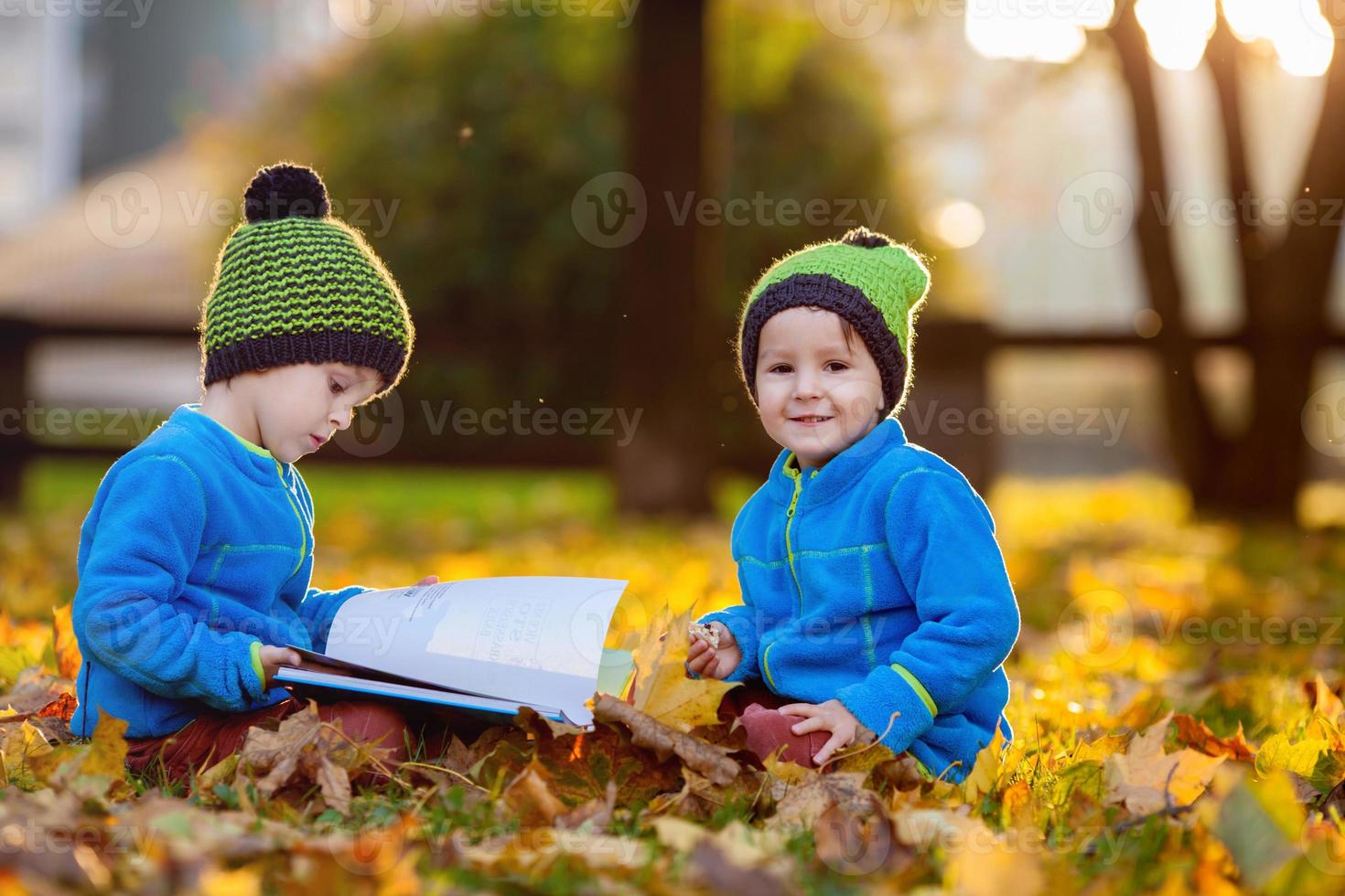 zwei Jungen, die nachmittags ein Buch über Rasen lesen foto