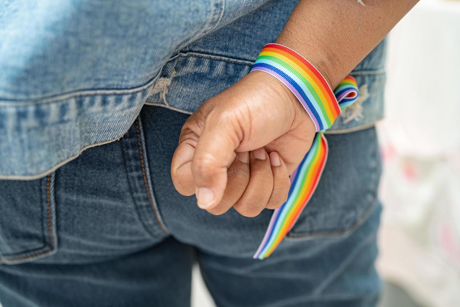 asiatische dame mit regenbogenflaggenarmbändern, symbol des lgbt-stolzmonats, feiert jährlich im juni die sozialarbeit von schwulen, lesbischen, bisexuellen, transgendern und menschenrechten. foto