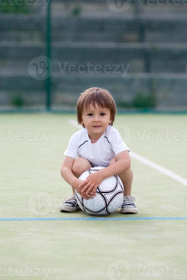 süßer kleiner Junge, Fußball spielend foto