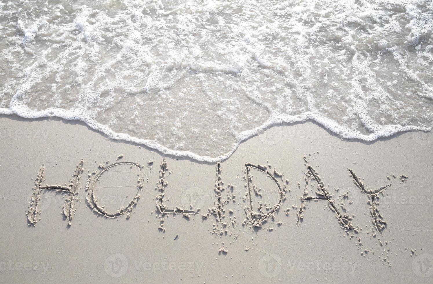 das Wort Urlaub in Großbuchstaben in den Sand geschrieben. foto