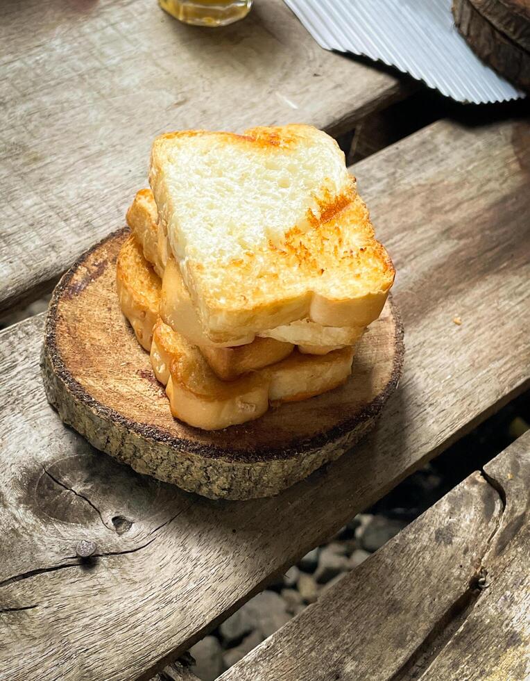 Brotscheiben werden leicht gebacken und auf Holzplatten gestapelt. Holzhintergrund für ein ästhetisches Aussehen. kann für Hintergründe oder Werbung verwendet werden. foto