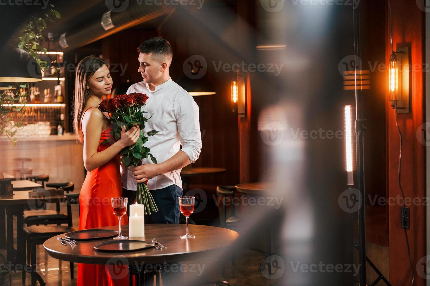 mit Blumen stehen. Romantisches Paar isst im Restaurant zu Abend foto