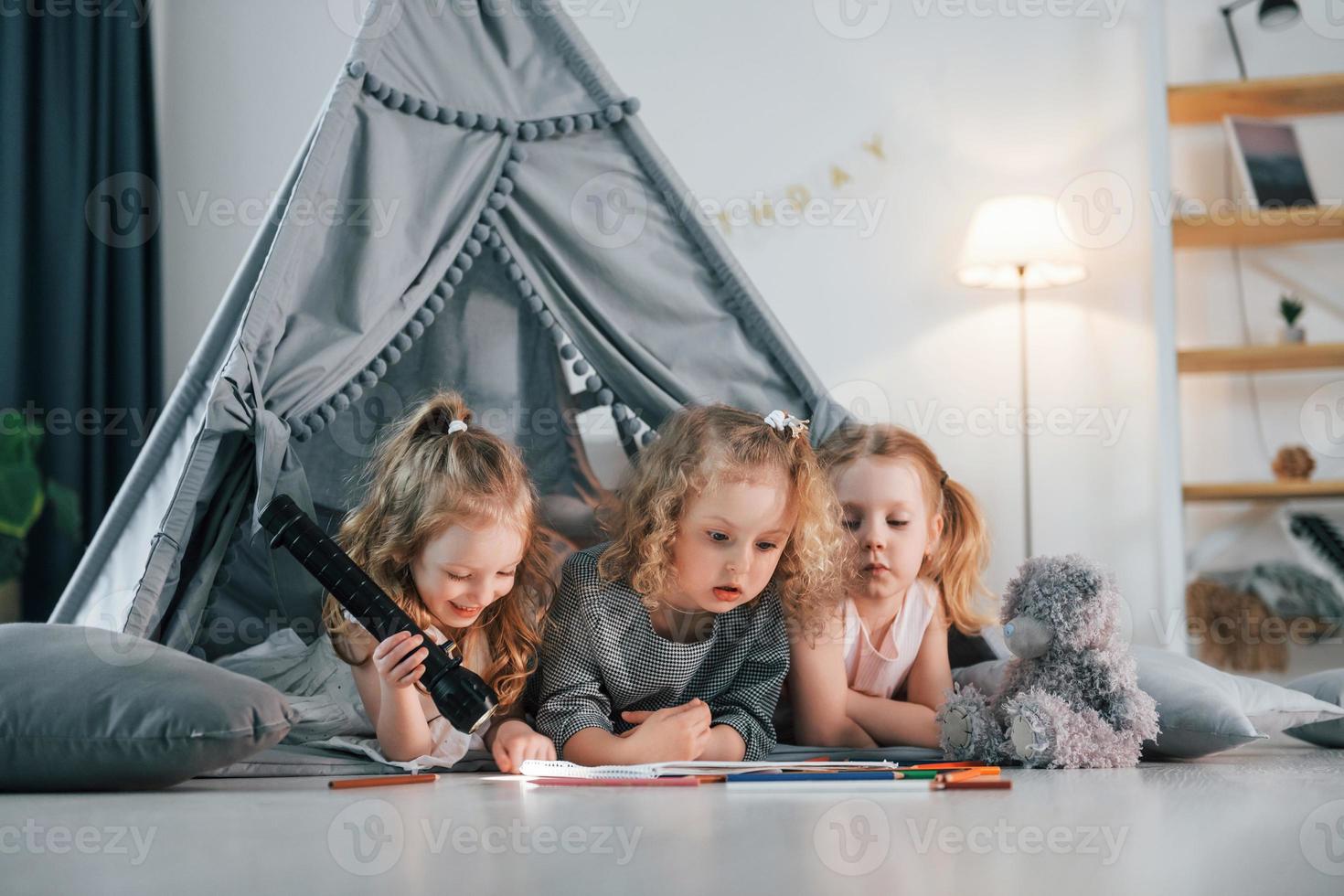 Zeichnen lernen. Mädchen legt sich im Zelt hin. Gruppe von Kindern ist tagsüber zusammen zu Hause foto