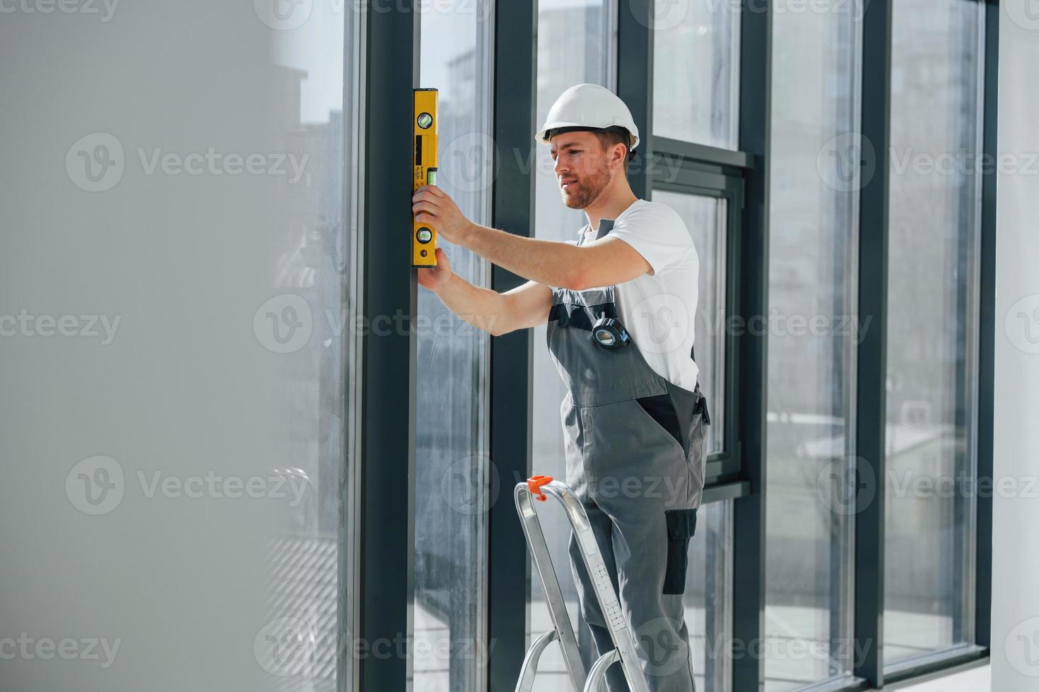 mit Führer in der Nähe von Fenstern. Der Handwerker arbeitet drinnen im modernen Raum foto