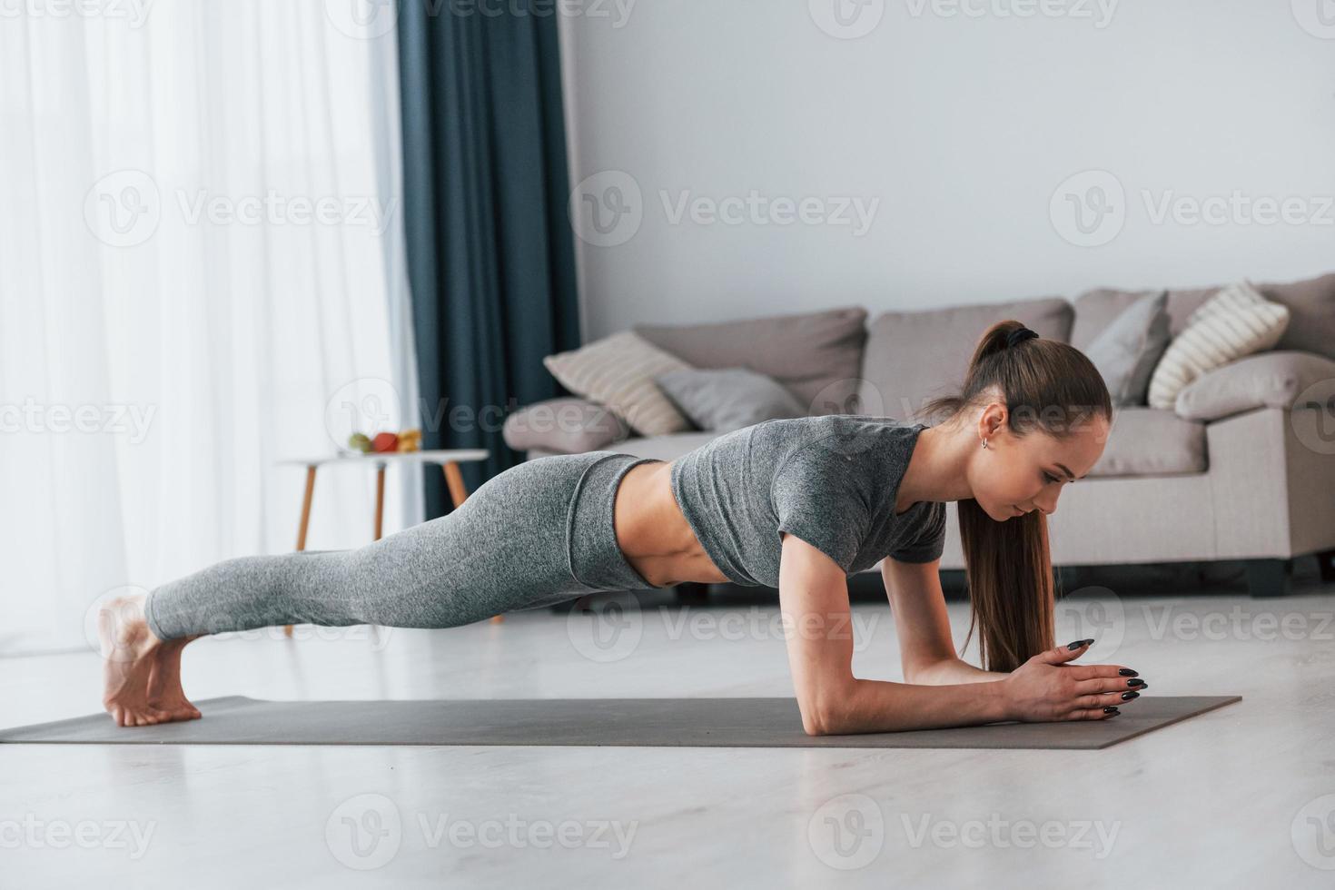 tagsüber. Übungen machen. junge frau mit schlankem körpertyp und in yogakleidung ist zu hause foto