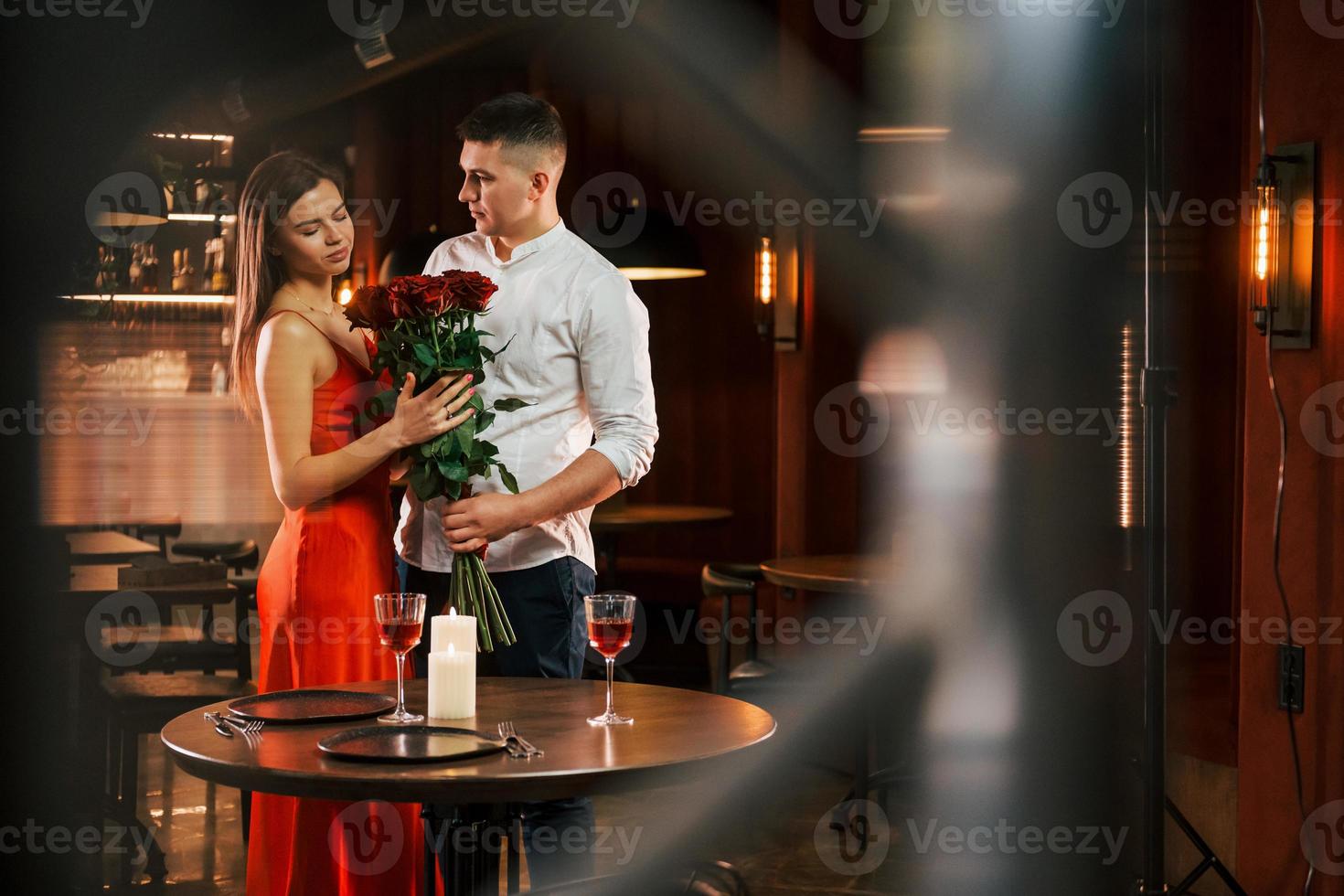 mit Blumen stehen. Romantisches Paar isst im Restaurant zu Abend foto