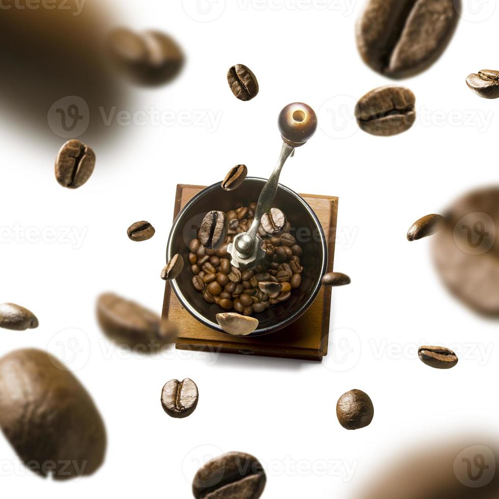 Kaffeemühle und Kaffeebohnen im Flug auf weißem Hintergrund foto