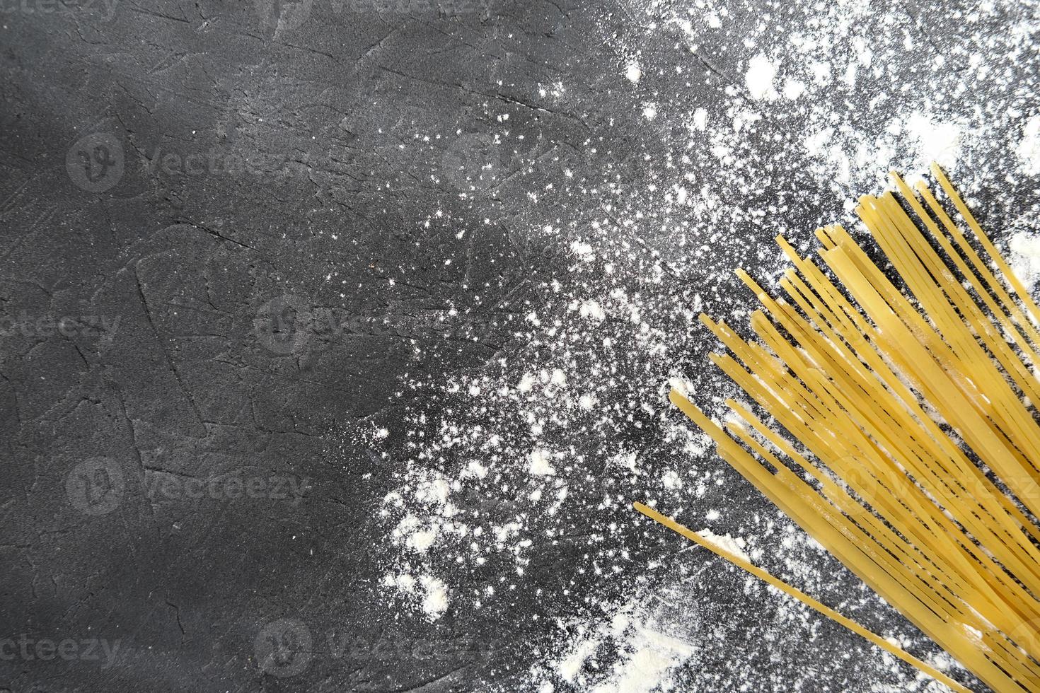 gelbe lange Spaghetti auf grauem Hintergrund mit Mehl. foto