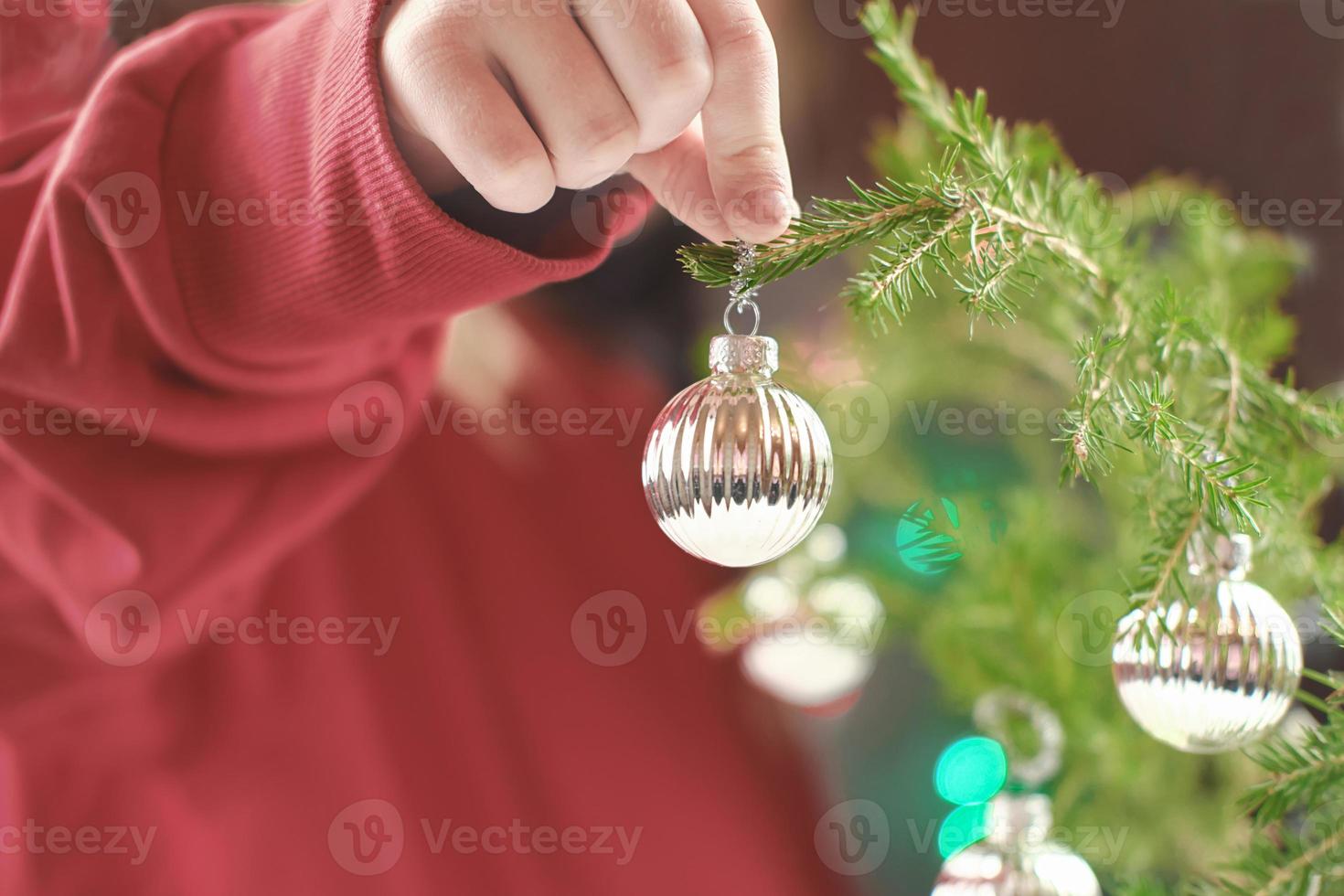 die hand des kleinen mädchens, die weihnachtskugel hält. foto