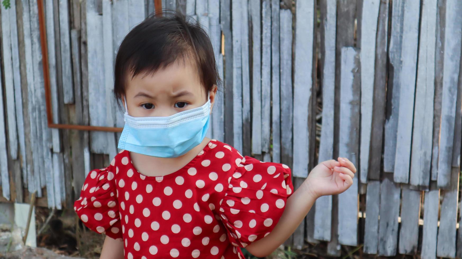 porträt eines unglücklichen und besorgten, ängstlichen asiatischen mädchens, das eine schützende gesichtsmaske trägt, die im freien steht. foto